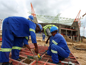 Строители на фоне стадиона "Мбомбела". Фото ©AFP