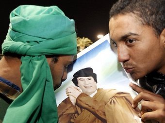 Сторонники Каддафи целуют его портрет на акции в поддержку лидера. Фото ©AFP