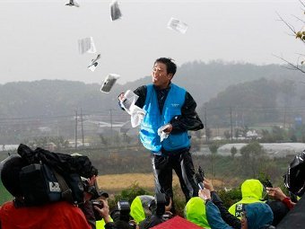 Активист из Южной Кореи разбрасывает листовки после блокировки парка в городе Пхаджу. Фото ©AP