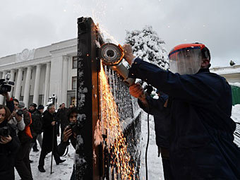 Андрей Тягнибок пилит забор у здания Верховной Рады. Фото ©AFP
