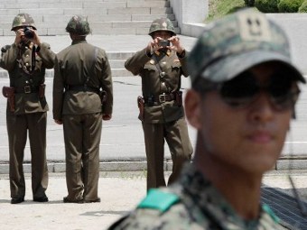 Северокорейские пограничники (на заднем плане) и южнокорейский пограничник. Фото ©AFP
